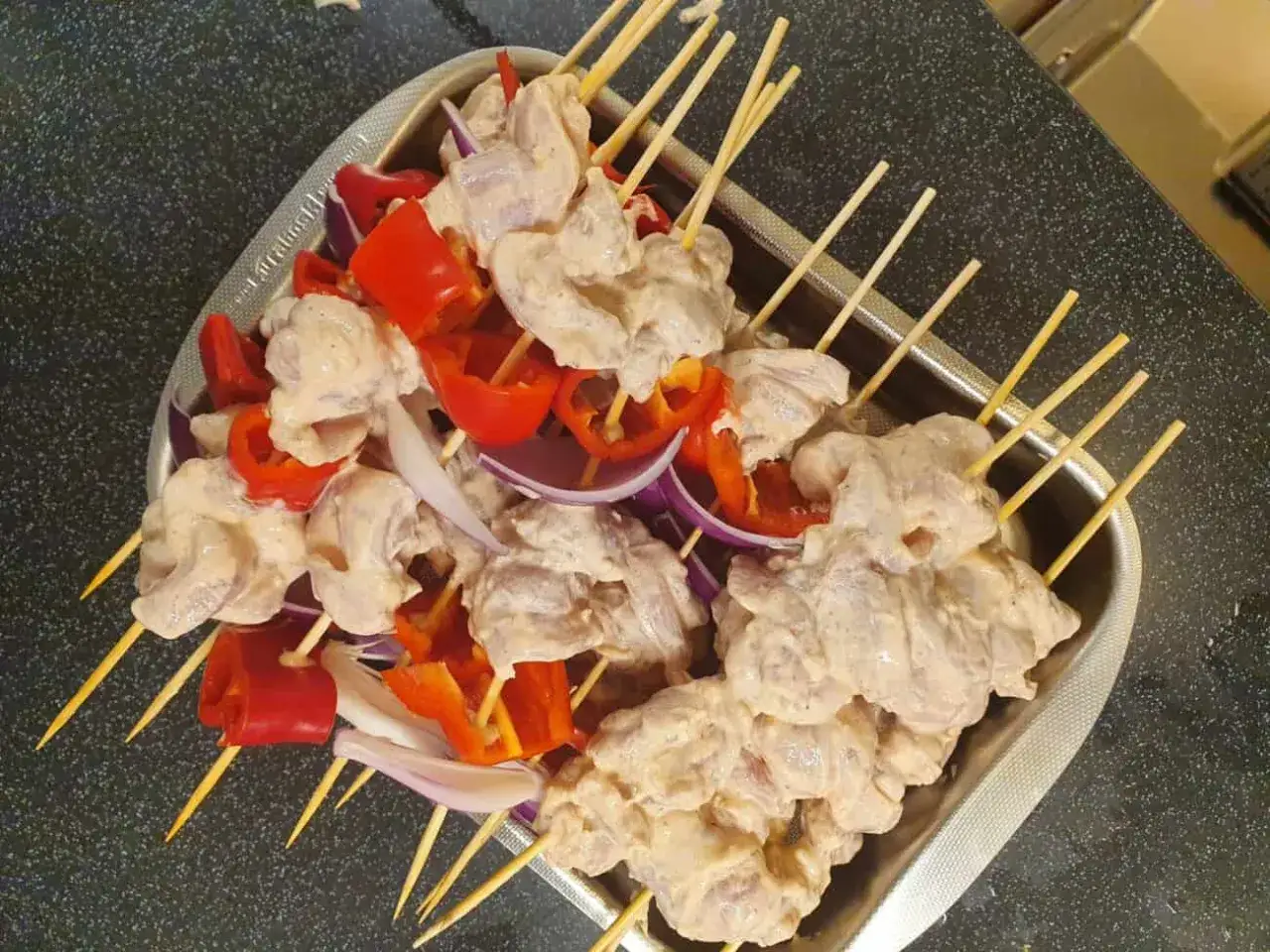 Shish tawook-spett p&aring; spett med kyckling, r&ouml;d paprika och l&ouml;k, redo att grillas.