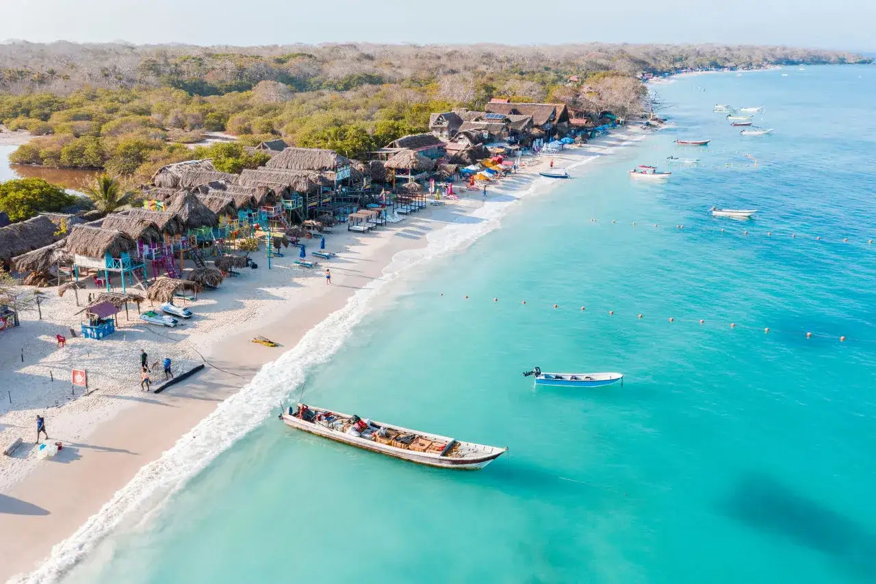Rajska plaża w Cartagena de Indias z kolorowymi chatkami, łodziami i turkusową wodą.
