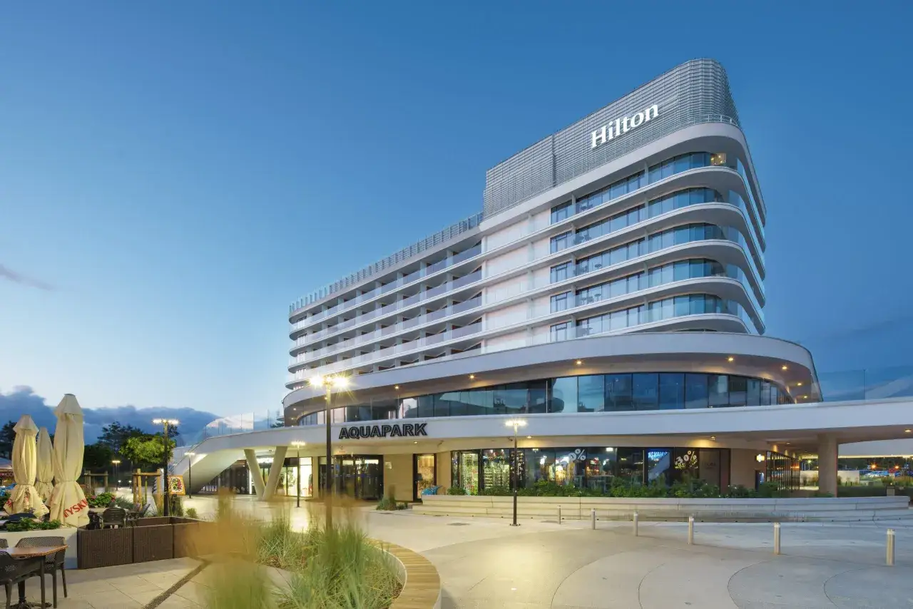 Nowoczesny hotel 5 gwiazdkowy nad morzem, z widocznym napisem Hilton i Aquapark.
