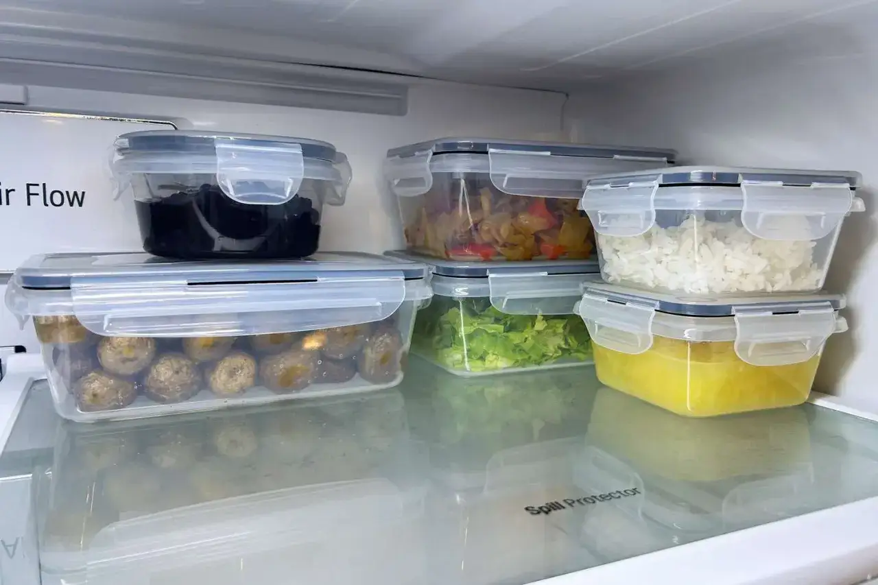 Sześć pojemników z jedzeniem w lodówce: ziemniaki, czarne fasolki, warzywa, ryż, sałata i żółty sos. Idealne meal prep przepisy.