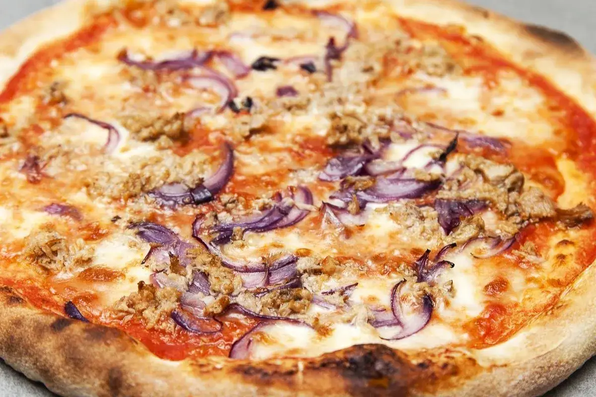 Pizza tonno e cipolla, con pomodoro, mozzarella filante, tonno sminuzzato e anelli di cipolla rossa.