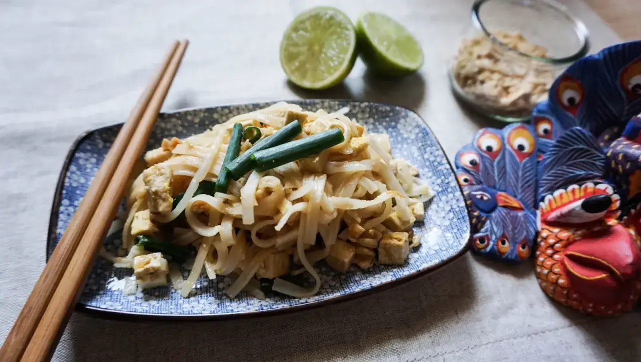 Oryginalny przepis na pad thai: makaron ryżowy z tofu, szczypiorkiem i orzeszkami ziemnymi, podany z limonką.