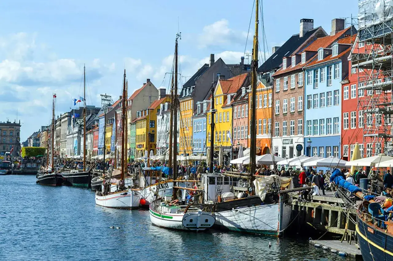 Kolorowe kamienice nad kanałem w Nyhavn, z żaglowcami zacumowanymi przy nabrzeżu.
