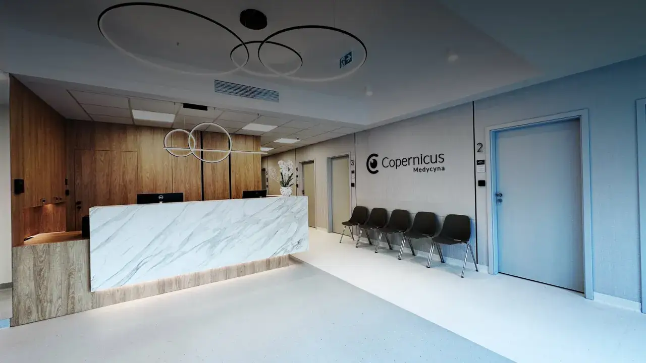 Nowoczesne wnętrze recepcji kliniki medycznej Copernicus z marmurowym blatem i wygodnymi krzesłami.