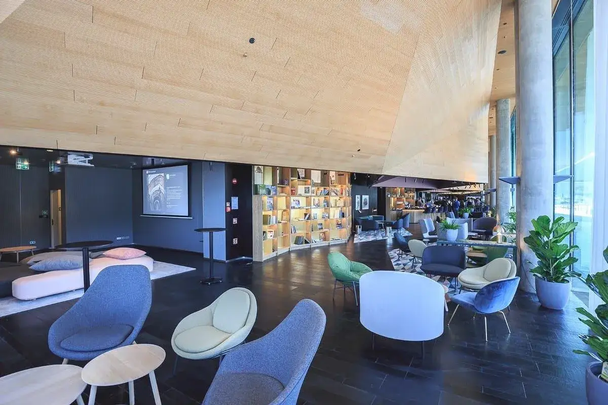 Nowoczesne wnętrze z wygodnymi fotelami i regałami pełnymi książek w Renaissance Hotels Warszawa.