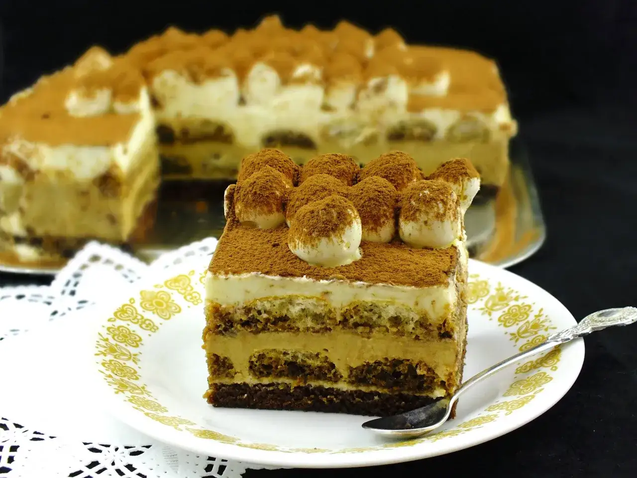 Pyszny sernik tiramisu, warstwowy deser z kremem i biszkoptami, posypany kakao.