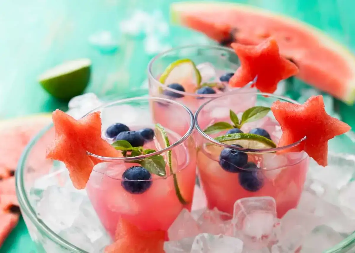 Refrescantes c&oacute;cteles de sand&iacute;a con lim&oacute;n, ar&aacute;ndanos y rodajas de lima, adornados con estrellas de sand&iacute;a.