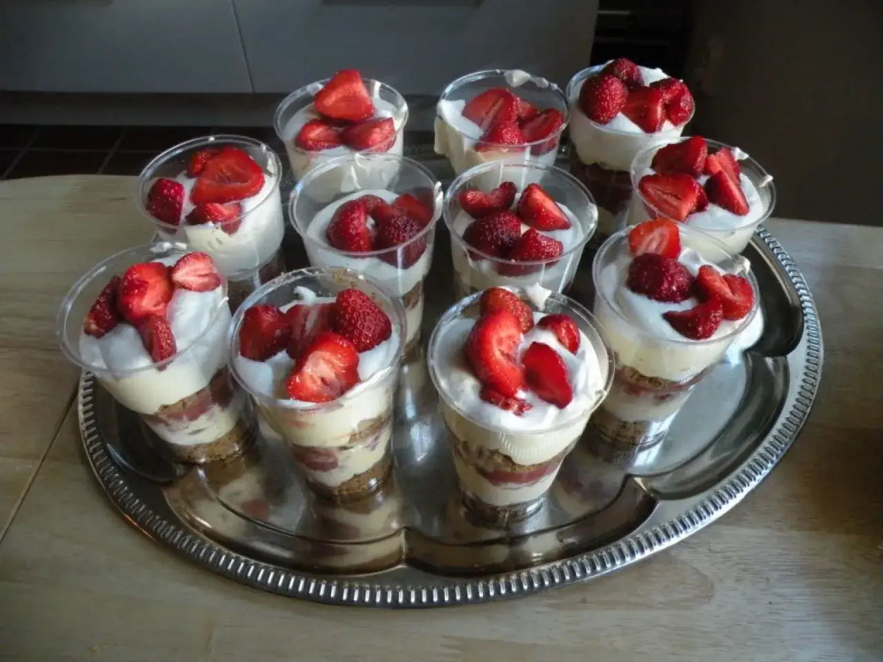 En bricka med flera portionsglas fyllda med kr&auml;mig glass, smulade kex och f&auml;rska jordgubbar. Perfekt f&ouml;r en sommardessert!