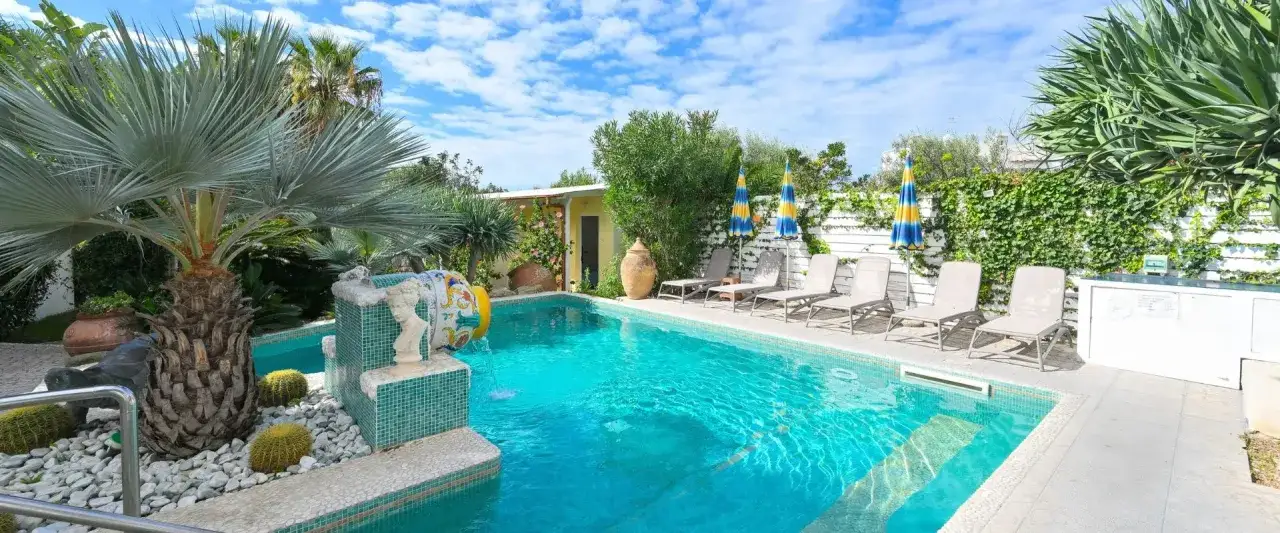 Piscina cristallina e lettini prendisole al **hotel La Villa Ischia**, circondati da palme e vegetazione lussureggiante.
