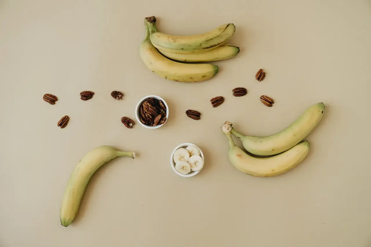 Dojrzały banan kcal, orzechy pekan i plasterki banana na jasnym tle. Zdrowa przekąska.