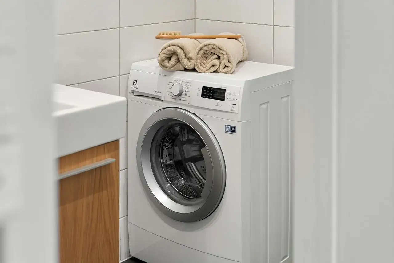 Machine &agrave; laver blanche avec serviettes et brosse sur le dessus. Un bon entretien prolonge la dur&eacute;e de vie machine &agrave; laver.