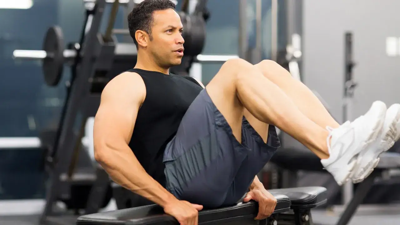 Un homme fait un exercice abdominal sur un banc de musculation, concentré sur son entraînement.