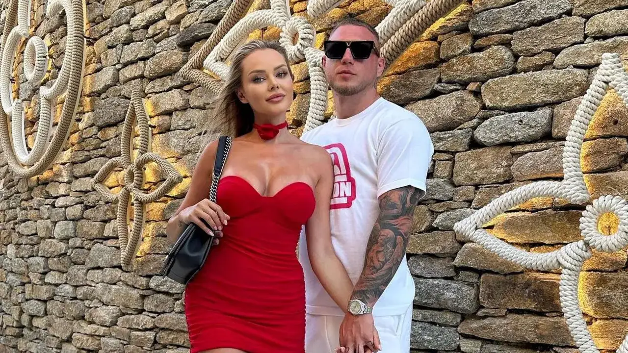 Ola Ciupa i Kubanczyk w czerwonych kreacjach pozują na tle kamiennej ściany z dekoracjami z liny.