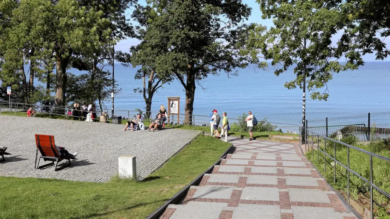 Relaks nad morzem, idealne tanie wczasy dla emerytów. Ludzie odpoczywają na leżakach, podziwiając widok.