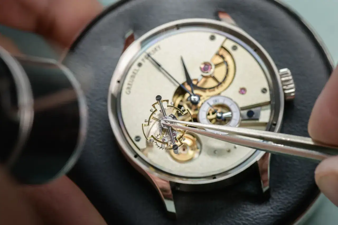 Detalle de un relojero ajustando un intrincado mecanismo de tourbillon. El