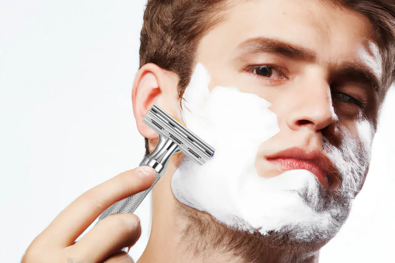 Hombre aplic&aacute;ndose espuma de afeitar para quitarse la barba con una maquinilla.