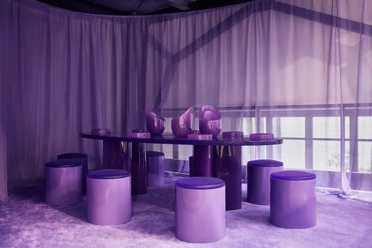 Ein Raum in verschiedenen Lilatönen. Der Tisch und die Hocker sind lila, was die Farbe lila bedeutungsvoll macht.