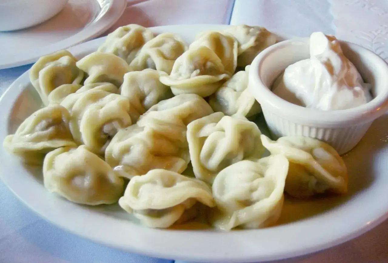 Talerz pełen parujących pierogów, co to za pyszność! Obok miseczka gęstej śmietany.