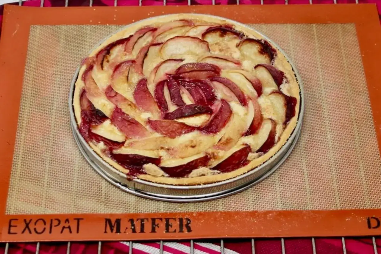 Tarte aux nectarines aux couleurs vives, disposées en spirale sur une pâte dorée. Un délice prêt à être dégusté.