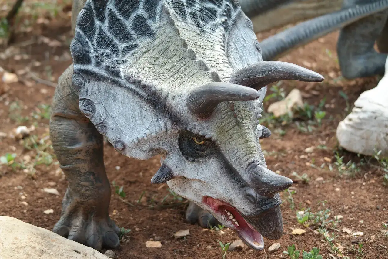 Dettaglio di un dinosauro con corna e bocca aperta, un'attrazione del zoo pi&ugrave; grande d'Italia.
