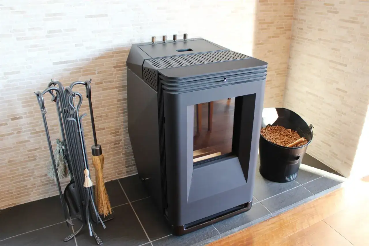 Estufa de pellets negra junto a un cubo de pellets y herramientas de chimenea. ¿Será el error 12 estufa pellets?