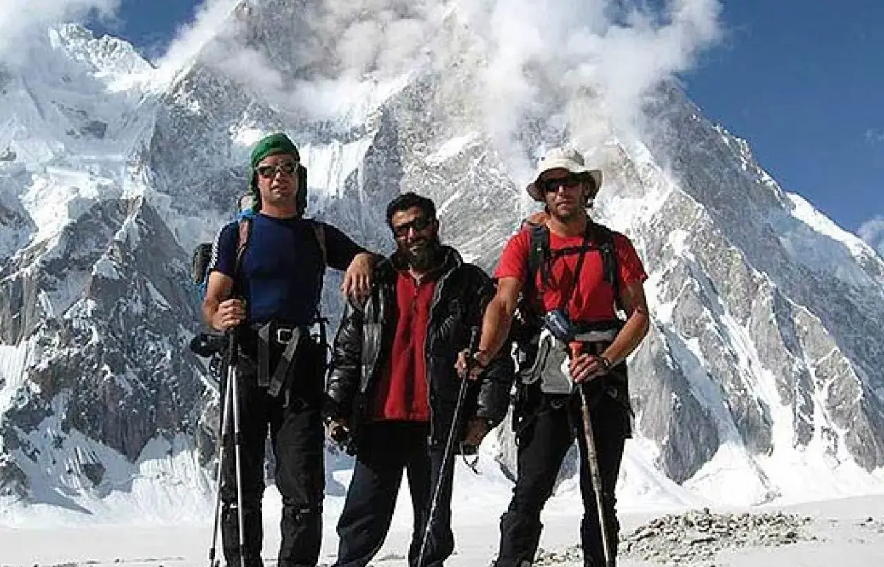 Oscar P&eacute;rez alpinista y dos compa&ntilde;eros posan con bastones de trekking ante un imponente pico nevado.