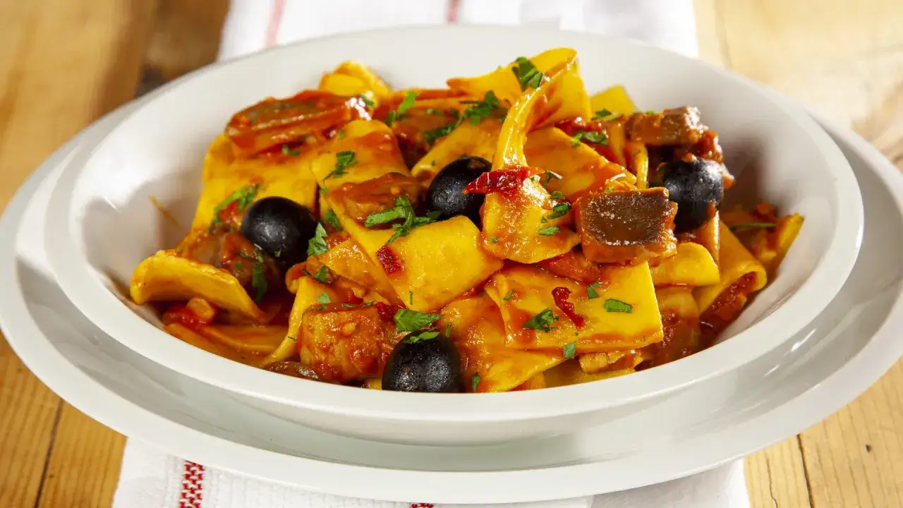 Piatto di fregnacce ricetta con sugo di pomodoro, olive nere e carne.