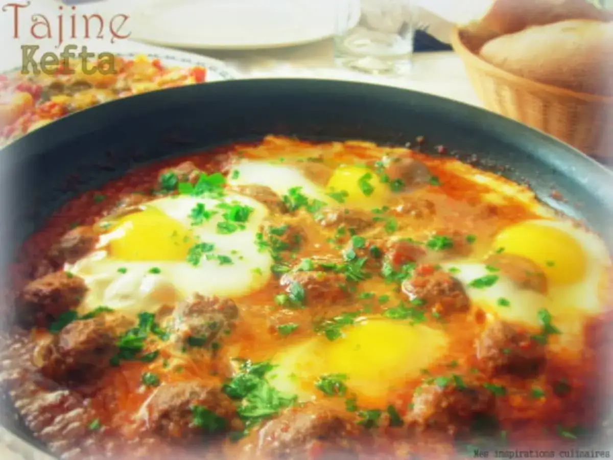 Un savoureux tajine kefta oeuf, garni de persil frais, mijote dans une sauce tomate épicée.