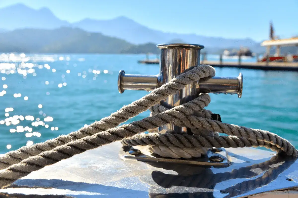 Corde &eacute;paisse enroul&eacute;e autour d'un taquet m&eacute;tallique sur un bateau, &eacute;voquant l'ancre, signification de stabilit&eacute; et de s&eacute;curit&eacute; en mer.