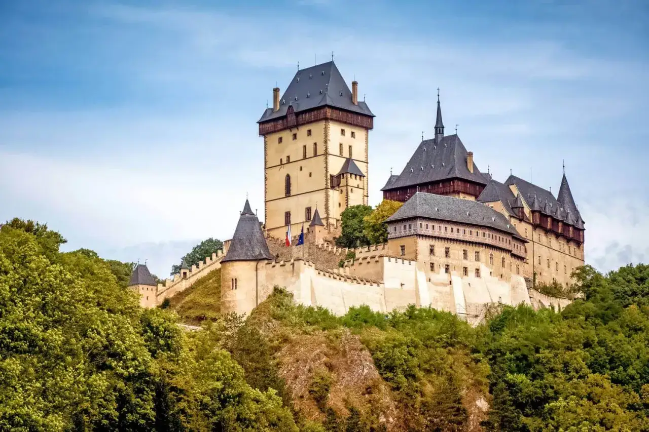Majest&auml;tische Burg Karl&scaron;tejn thront auf einem H&uuml;gel, umgeben von &uuml;ppigem Gr&uuml;n.
