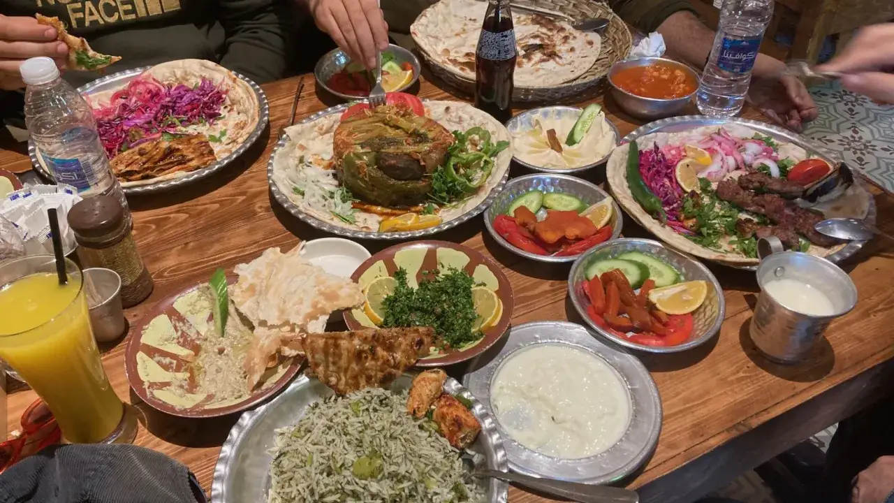 Ein Festmahl mit irakischer Kultur: K&ouml;stliche Mezze, gegrilltes Fleisch und Reis auf einem Holztisch.