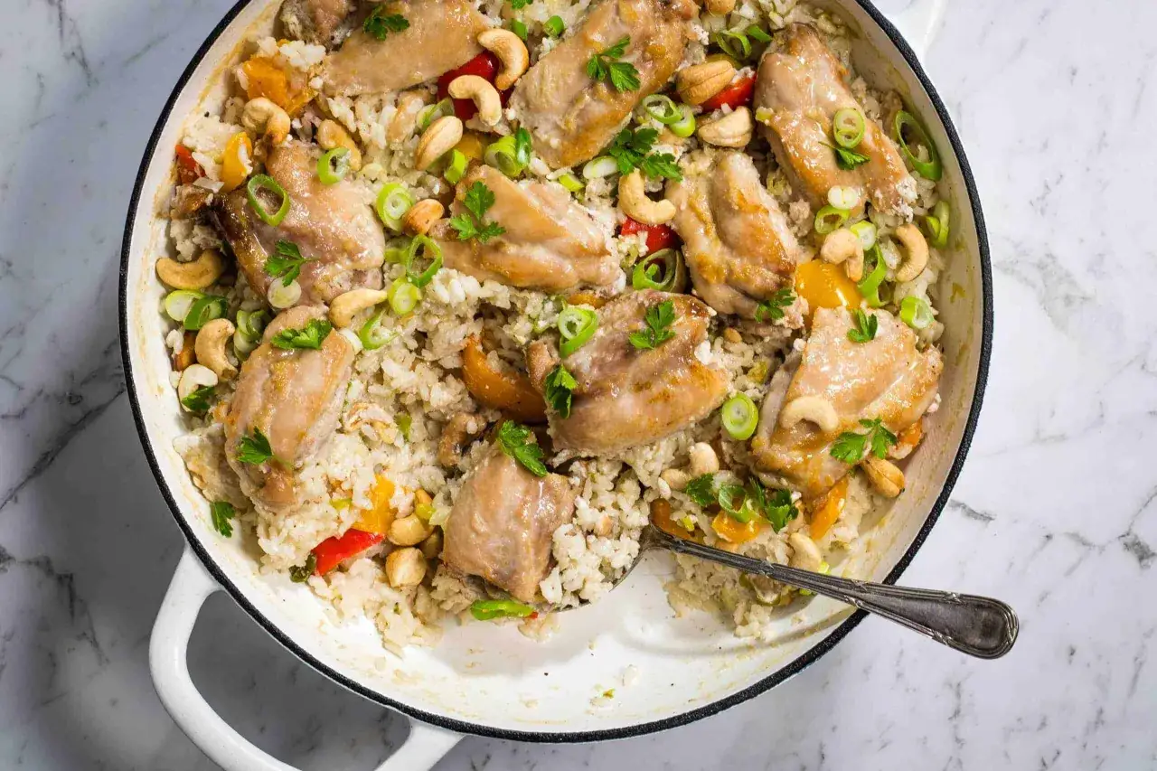 Un plat de poulet et riz coco, garni de noix de cajou, oignons verts et persil. Une recette savoureuse et colorée.