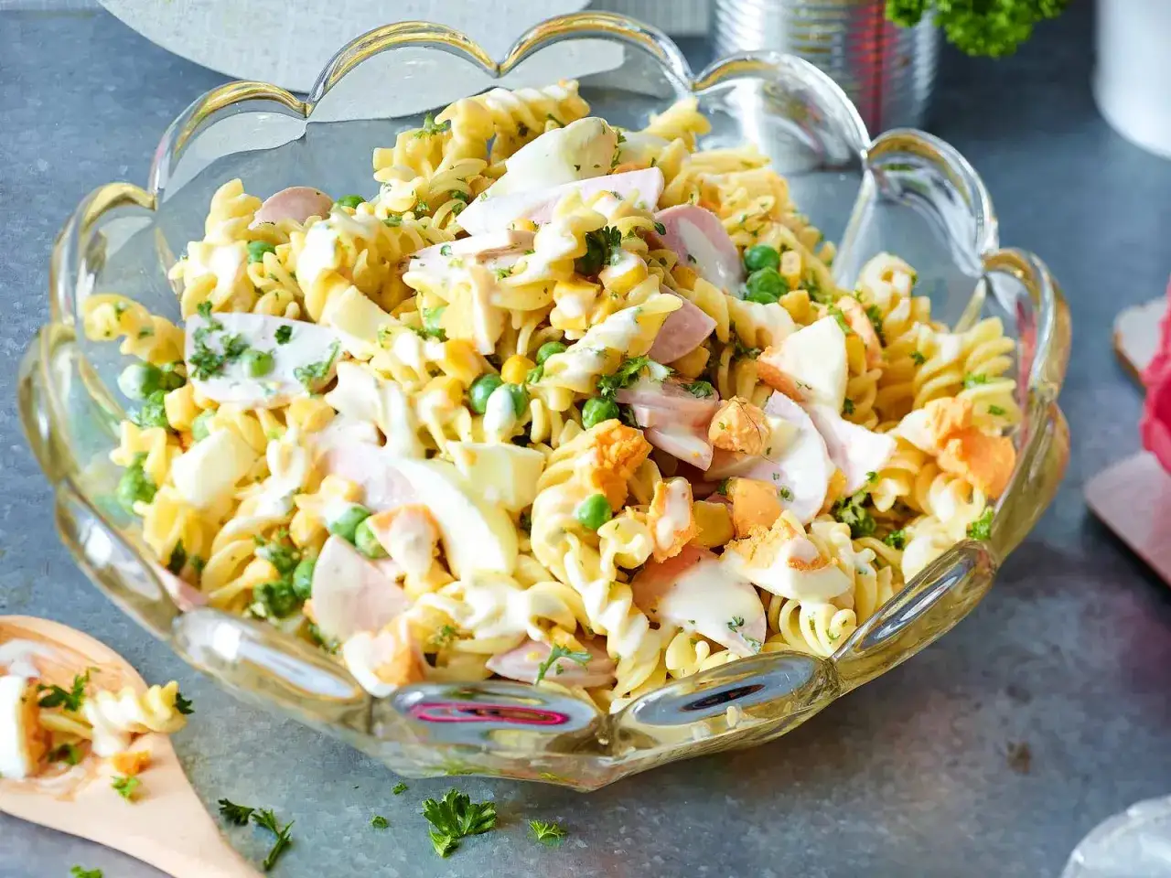 Ein k&ouml;stlicher nudelsalat mit mayo, gef&uuml;llt mit Erbsen, Ei und Schinken, serviert in einer Glassch&uuml;ssel.