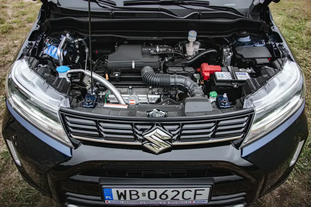 Silnik Suzuki Vitara Hybrid z otwartą maską. Widoczny akumulator, elementy układu dolotowego i chłodzenia.