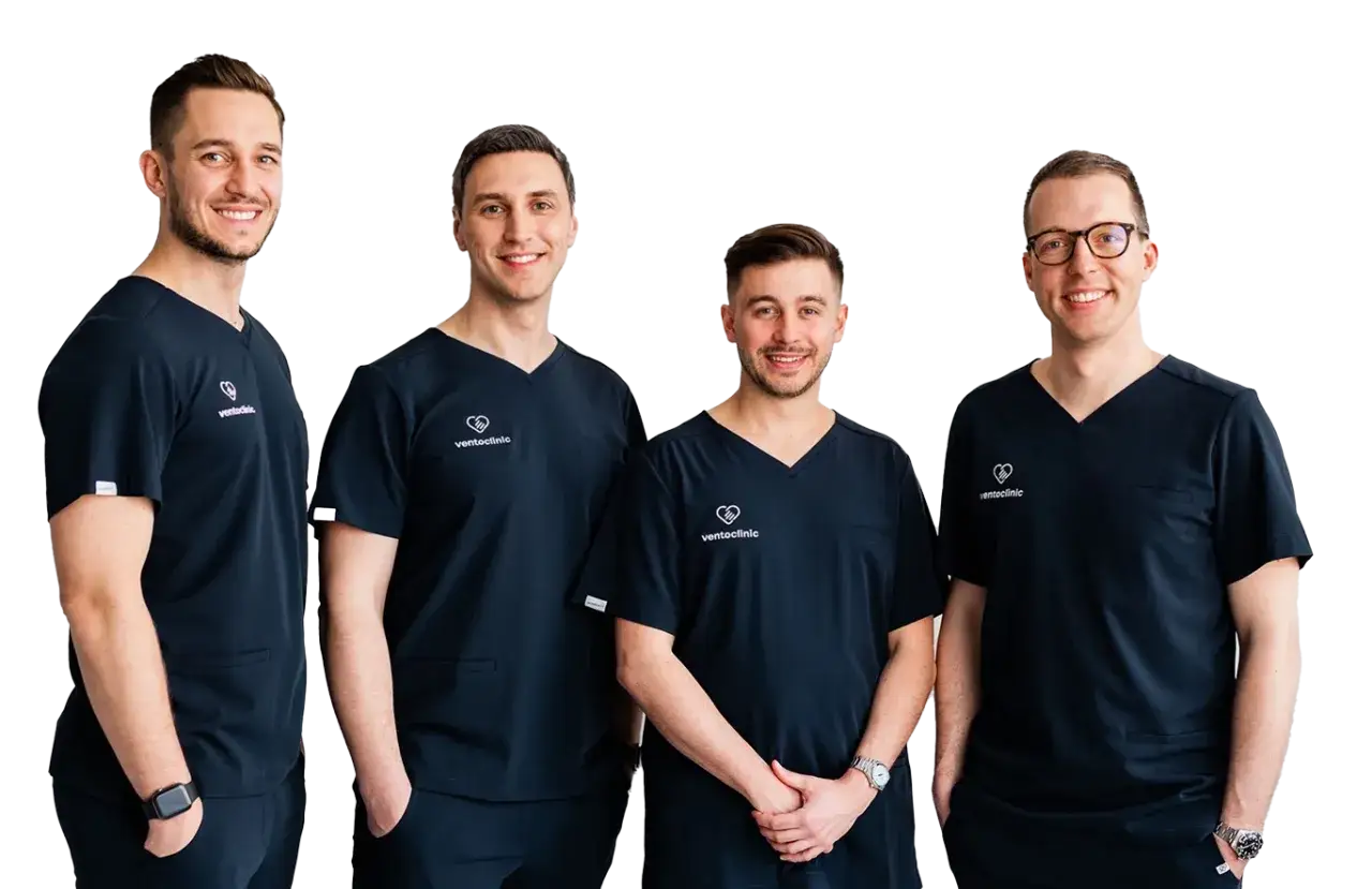 Czterech uśmiechniętych mężczyzn w granatowych medycznych uniformach, stojących na czarnym tle.