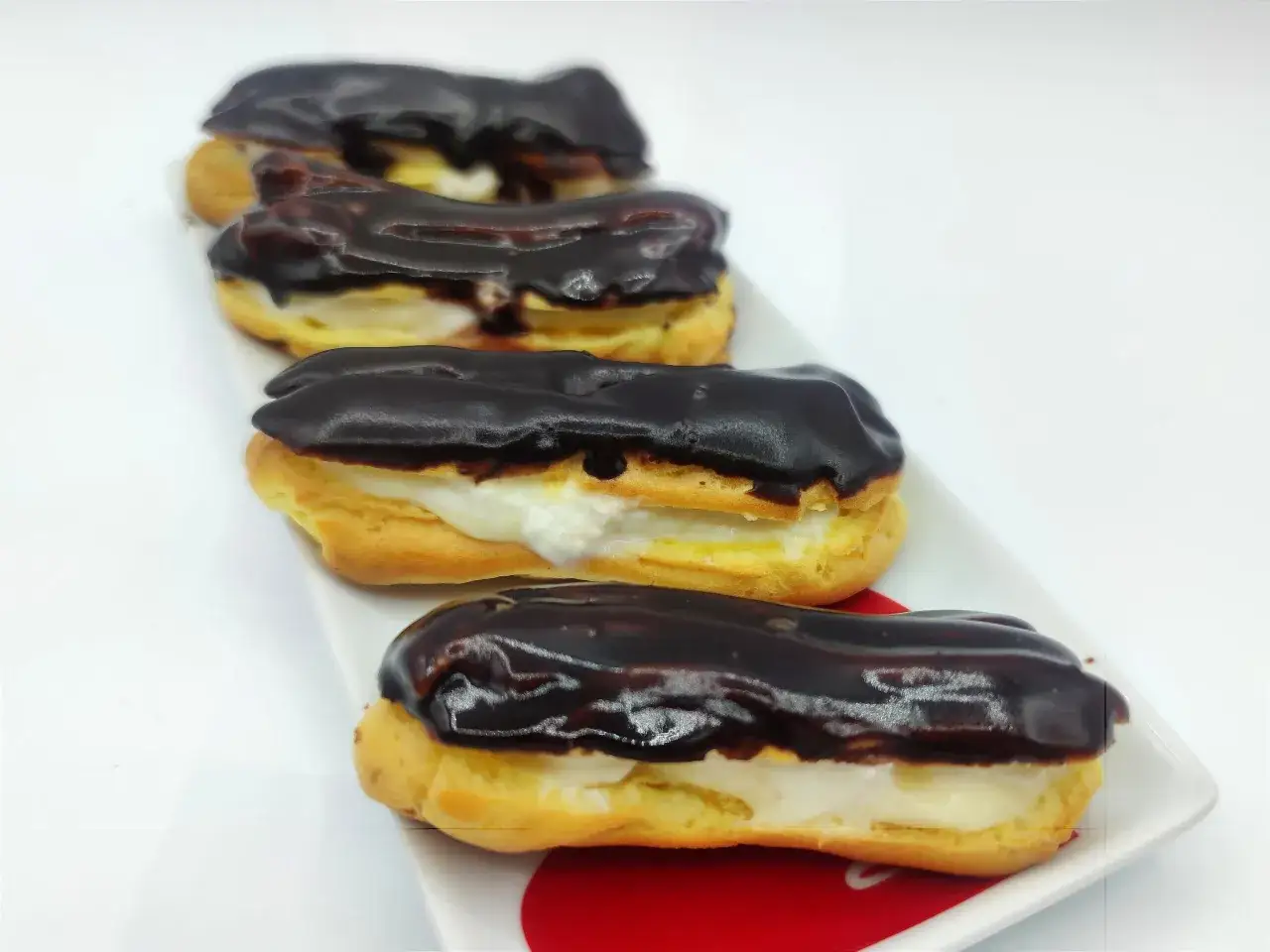 Quattro deliziosi &eacute;clair con crema e glassa al cioccolato, pronti per essere gustati. Una perfetta &eacute;clair ricetta.