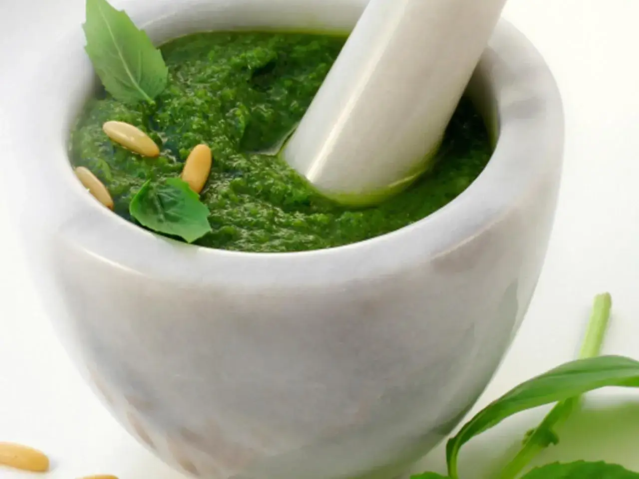 Frisches basilikum pesto in einem Marmormörser, garniert mit Pinienkernen und Basilikumblättern.