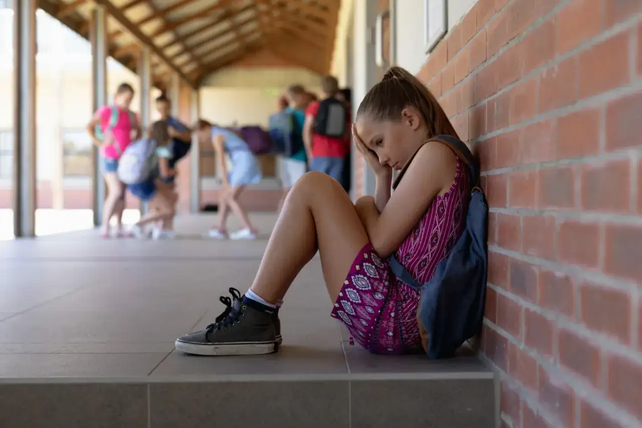 Ni&ntilde;a triste sentada en el suelo. &iquest;Qu&eacute; hacer si un ni&ntilde;o molesta a mi hijo?