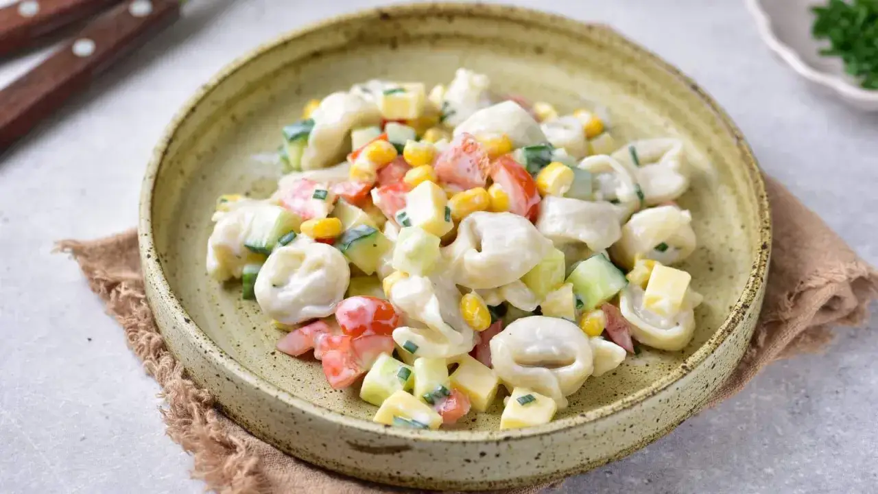 Szybka sałatka dla gości: tortellini z kukurydzą, pomidorkami, ogórkiem i serem w kremowym sosie.