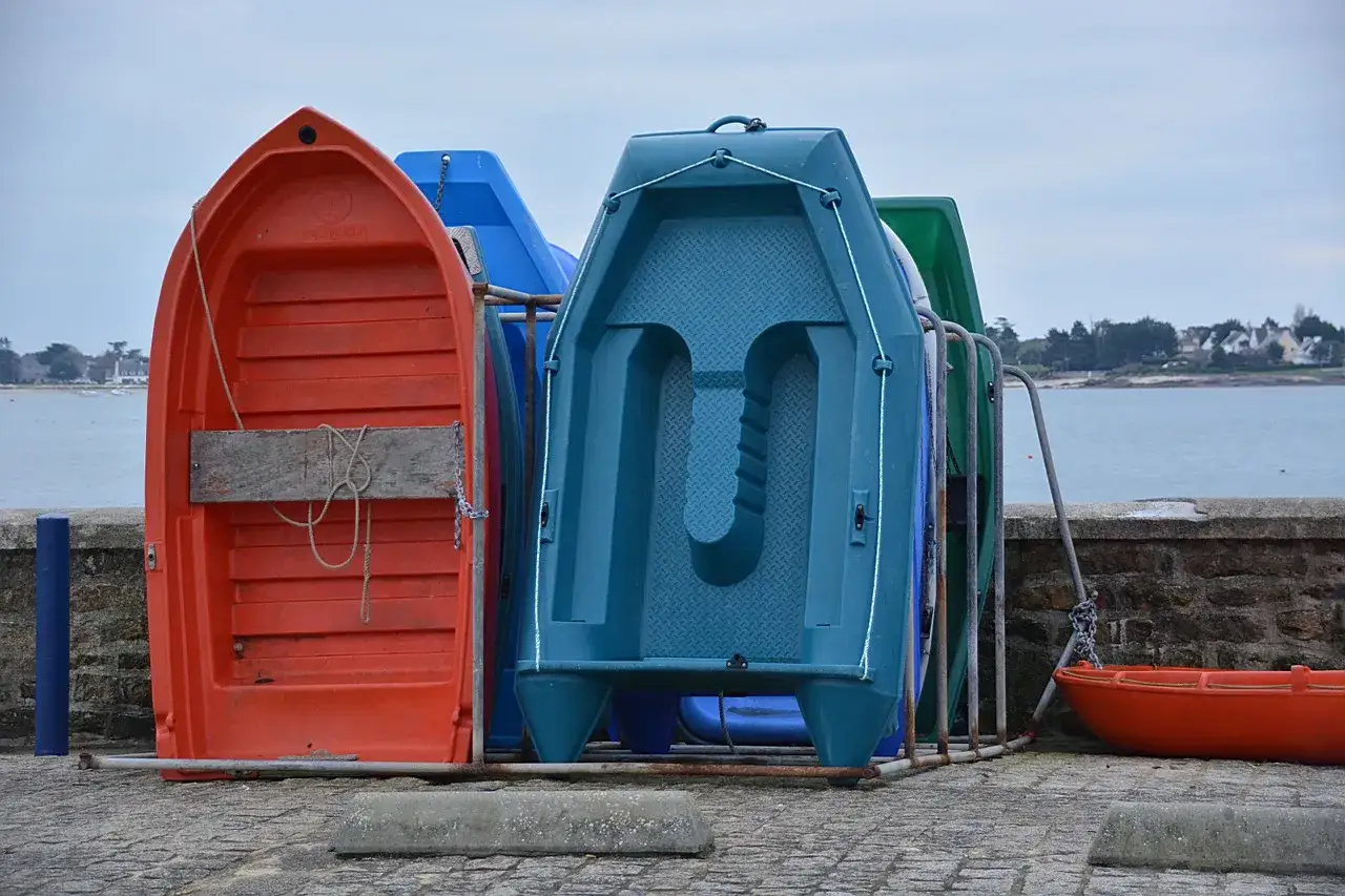 Plusieurs petites embarcations colorées, dont une annexe orange, sont rangées sur le quai, prêtes pour l'aventure sur la mer calme.