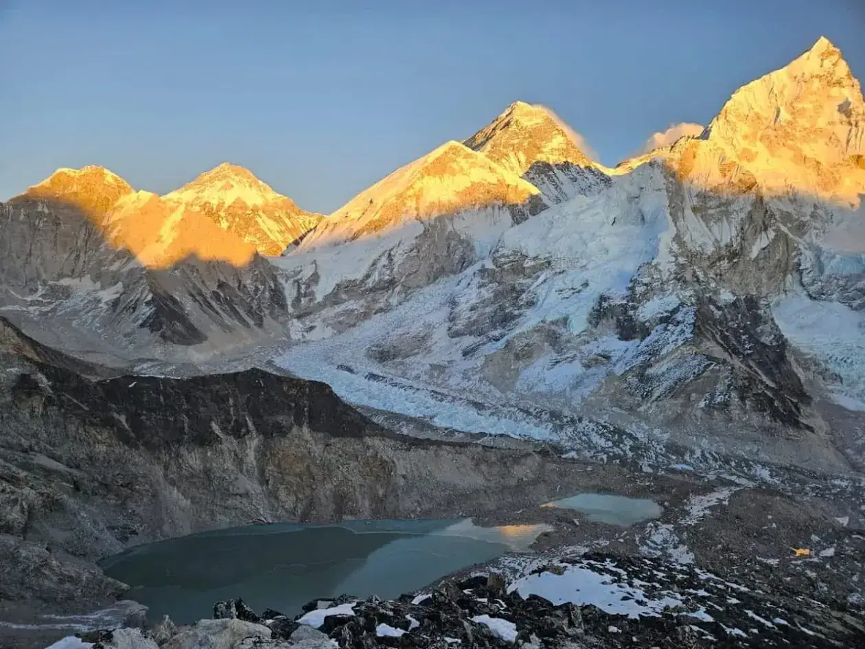 Złote światło poranka oświetla szczyty Everestu. Lodowce spływają ku turkusowym jeziorom u podnóża gór.