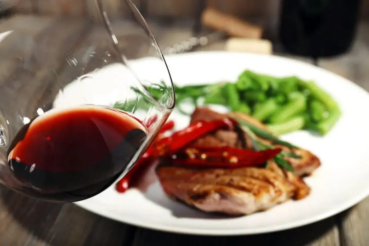 Czerwone wino w kieliszku, idealne do wieprzowiny z papryczkami chili i fasolką szparagową. Doskonały wybór na obiad.