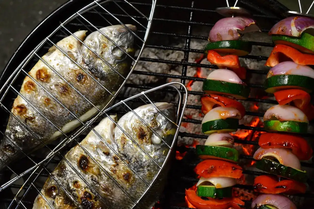 Zwei Dorade Fische auf dem Grill, daneben Gem&uuml;sespie&szlig;e mit Zucchini, Paprika und Zwiebeln. K&ouml;stlich!