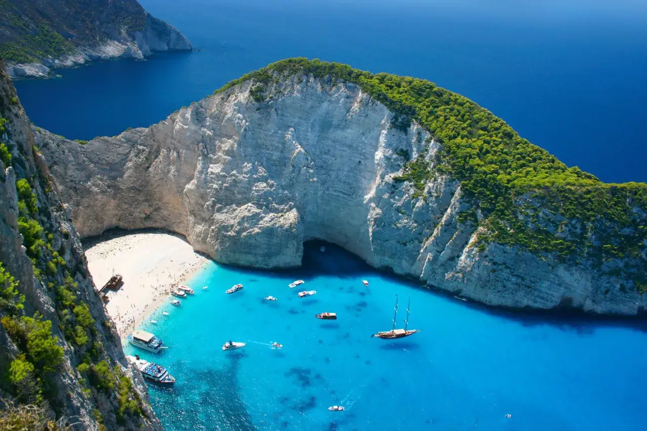 Widok na Navagio, słynną plażę w Grecji, z turkusową wodą, białym piaskiem i klifami.