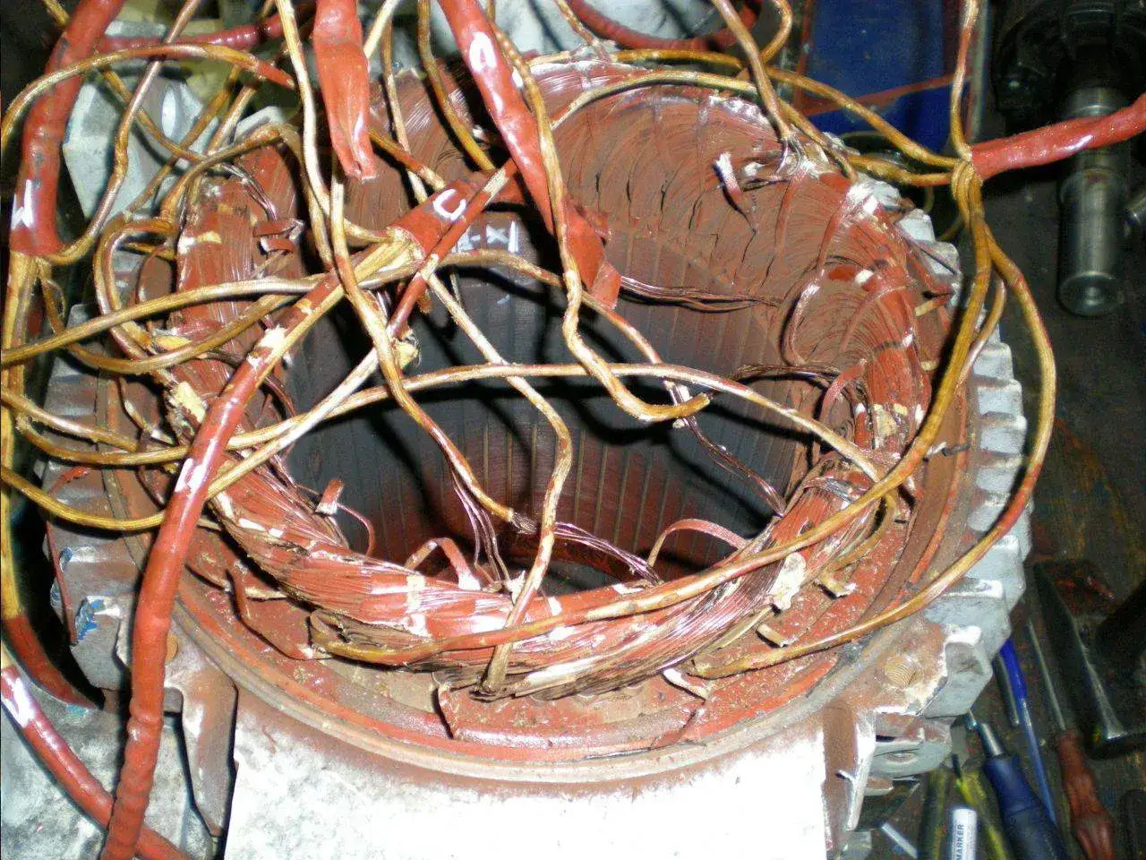 Uszkodzone uzwojenie silnika elektrycznego, kluczowe dla utrzymania ruchu w zakładzie produkcyjnym.