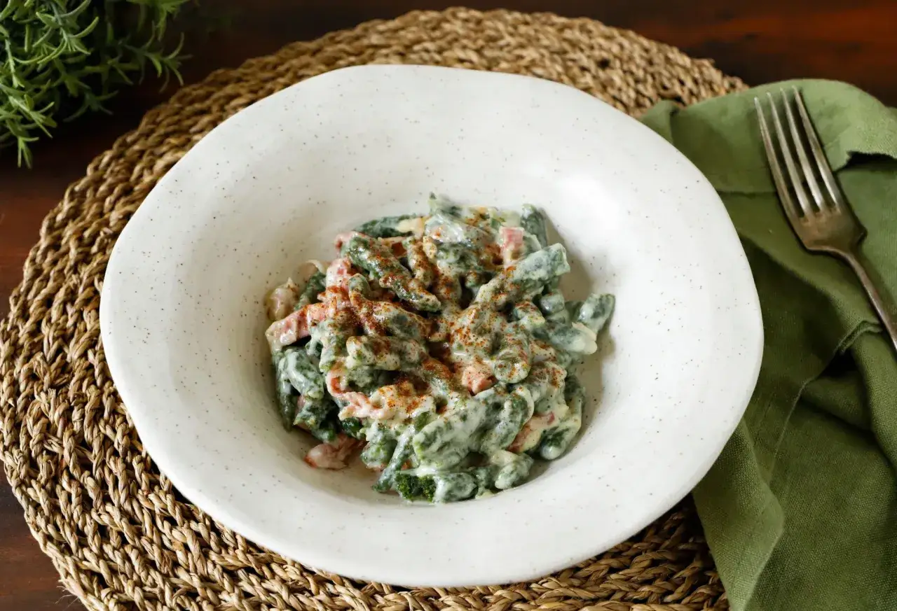 Un piatto di gnocchi verdi con panna e speck, un classico dei primi piatti trentini, spolverato di paprika.