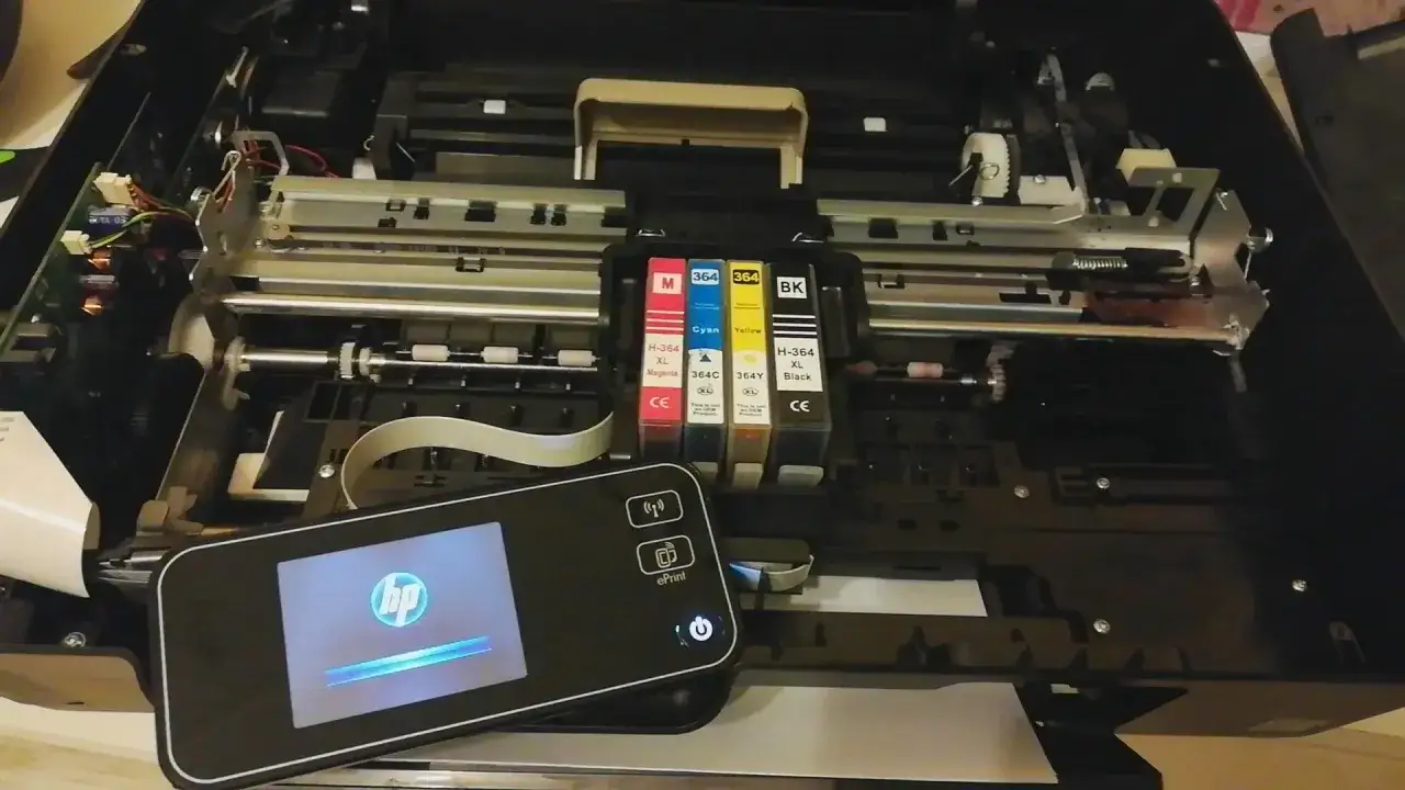 W drukarce HP 5520 widoczne są cztery tusze: magenta, cyan, ż&oacute;łty i czarny. Obok leży panel sterowania.