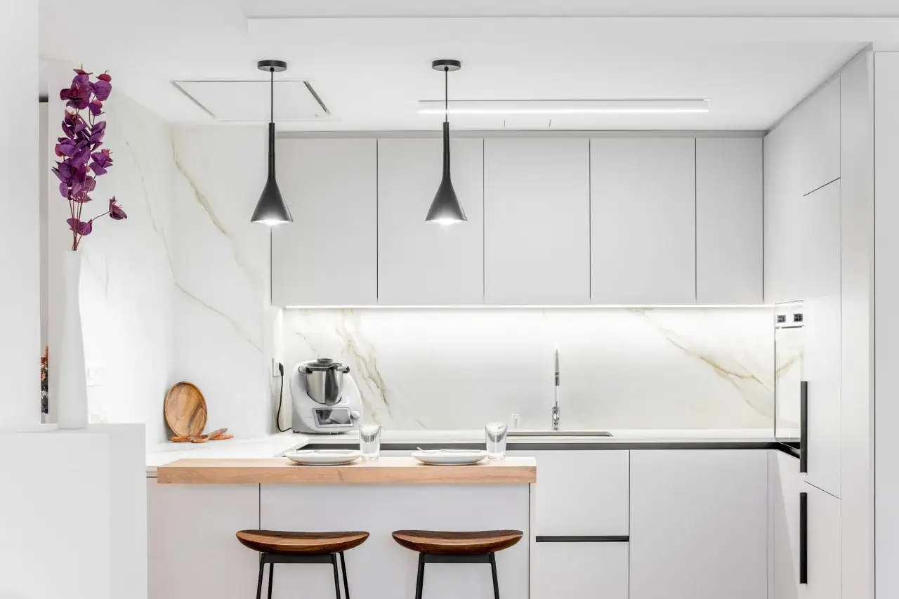 Cocinas abiertas al salón pequeñas con encimera de madera, taburetes y electrodomésticos modernos.