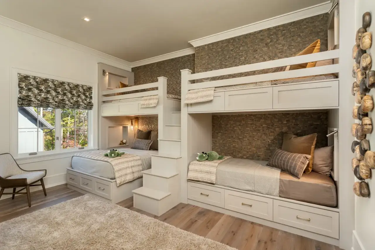 A cozy built in bunk room with two beds on each side, featuring storage drawers and a textured accent wall.