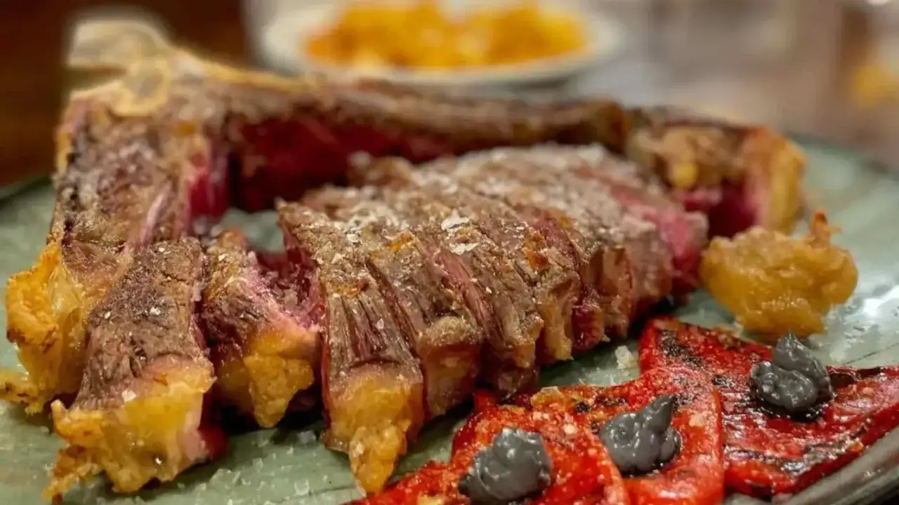 Jugosa chuleta a la brasa, acompañada de pimientos asados y patatas. Una delicia que justifica los mejores restaurantes Jaca.